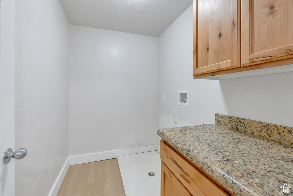 Laundry room with baseboards, cabinet space, hookup for a washing machine, and light wood-type flooring