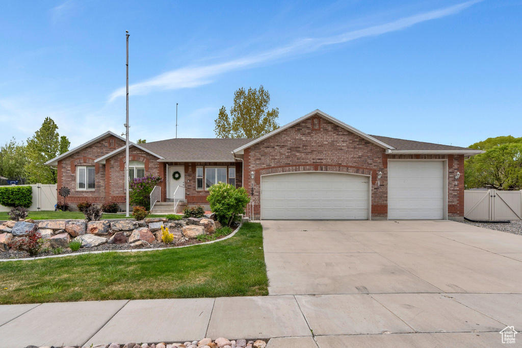 Ranch-style house with a gate, fence, concrete driveway, brick siding, and a garage