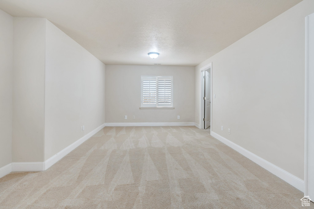 Spare room featuring light colored carpet and baseboards