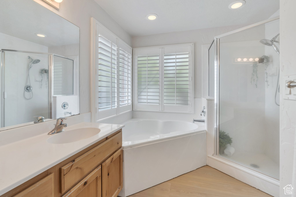 Bathroom featuring recessed lighting, wood finished floors, a shower stall, a garden tub, and vanity