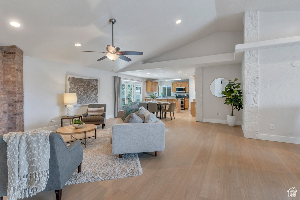 Living area with vaulted ceiling, ceiling fan, light wood-style flooring, baseboards, and recessed lighting