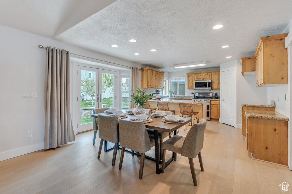 Dining space with light wood-style floors, baseboards, recessed lighting, and a textured ceiling