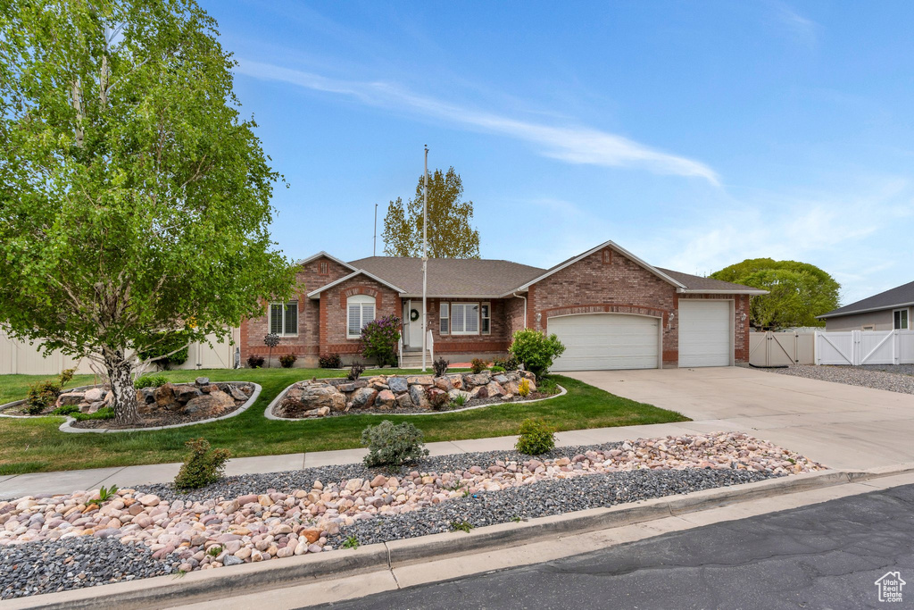 Single story home featuring a garage, concrete driveway, fence, a front yard, and brick siding