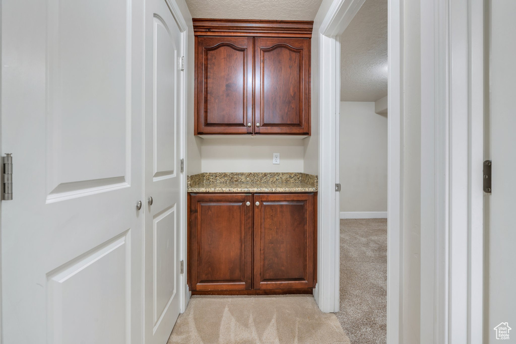Interior space featuring a textured ceiling, baseboards, and light carpet