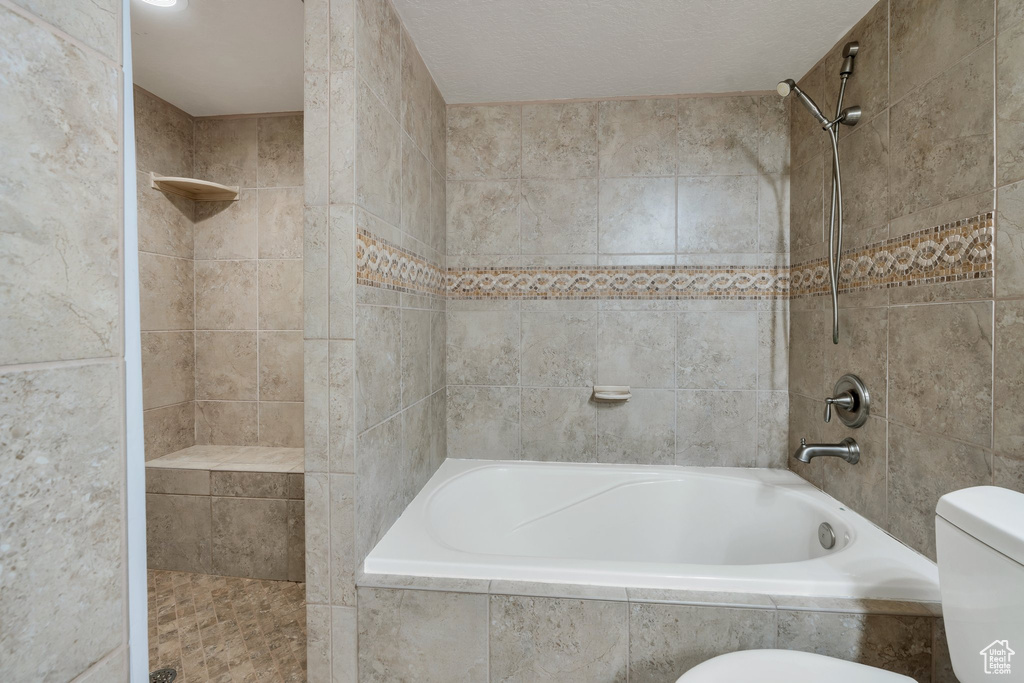 Bathroom featuring tiled shower / bath and toilet