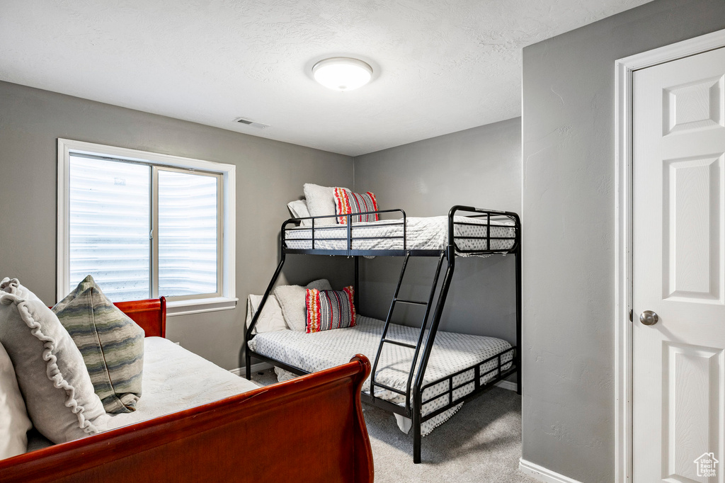 Carpeted bedroom with baseboards and visible vents
