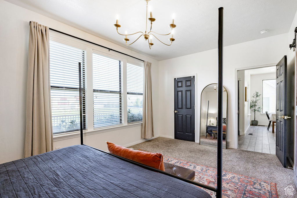 Carpeted bedroom with baseboards and a notable chandelier
