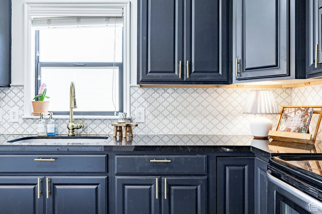 Kitchen with a sink, tasteful backsplash, dark countertops, stove, and blue cabinetry