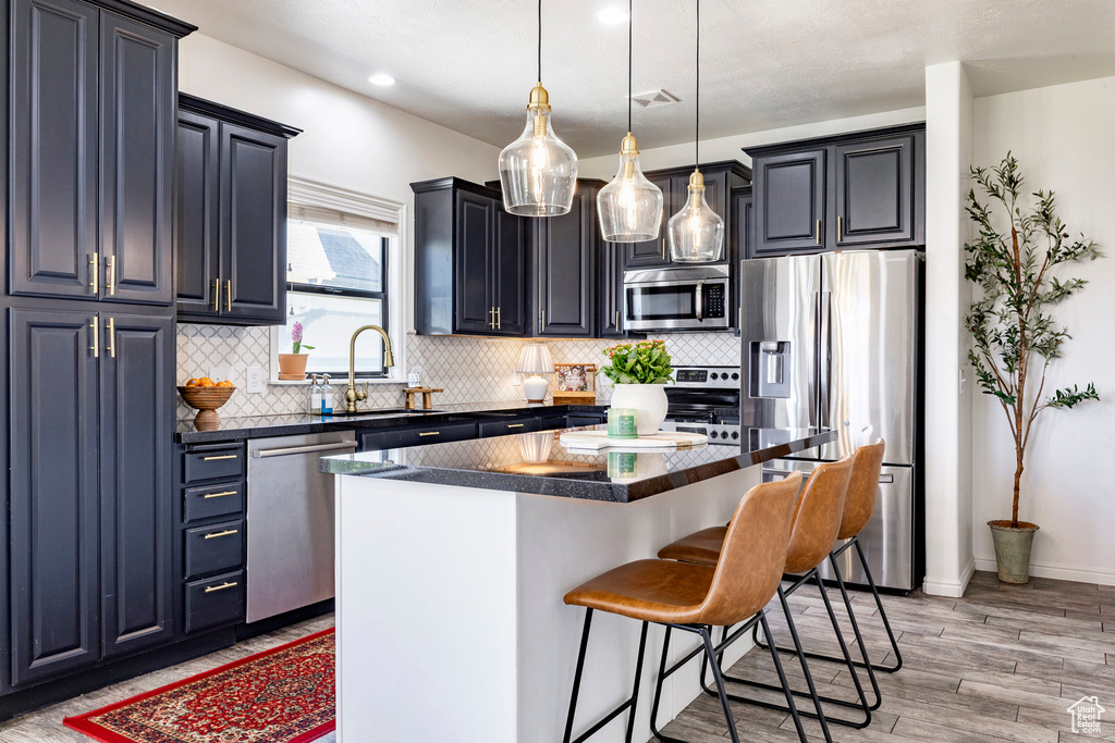 Kitchen featuring stainless steel appliances, a kitchen breakfast bar, a sink, and dark countertops