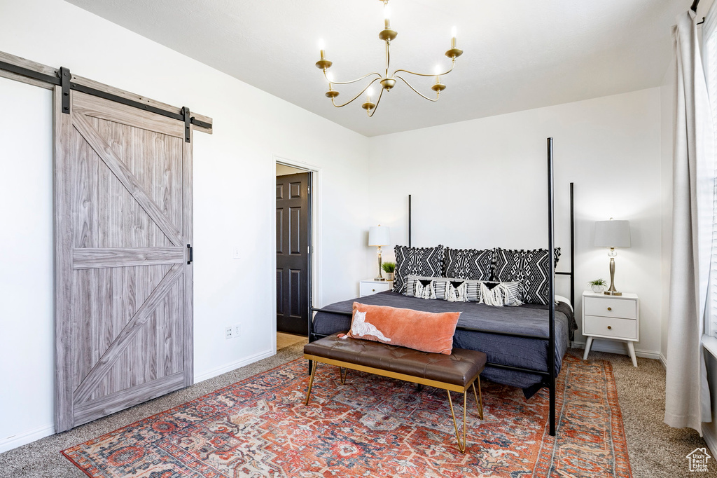 Bedroom with a barn door, carpet floors, baseboards, and an inviting chandelier
