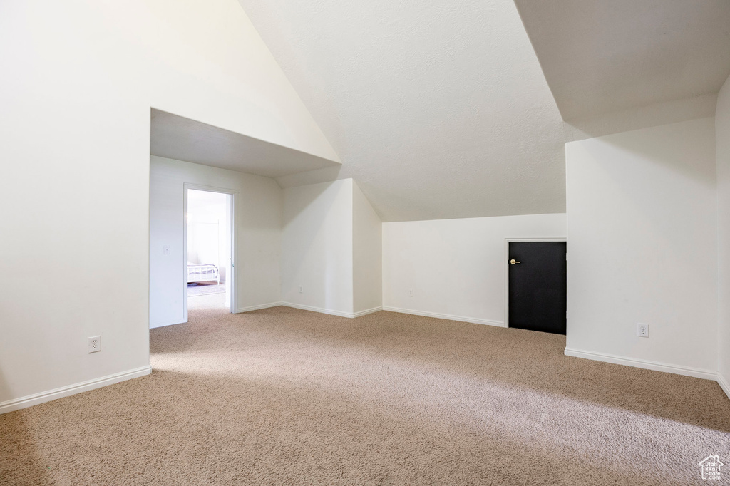 Additional living space featuring baseboards, lofted ceiling, and carpet