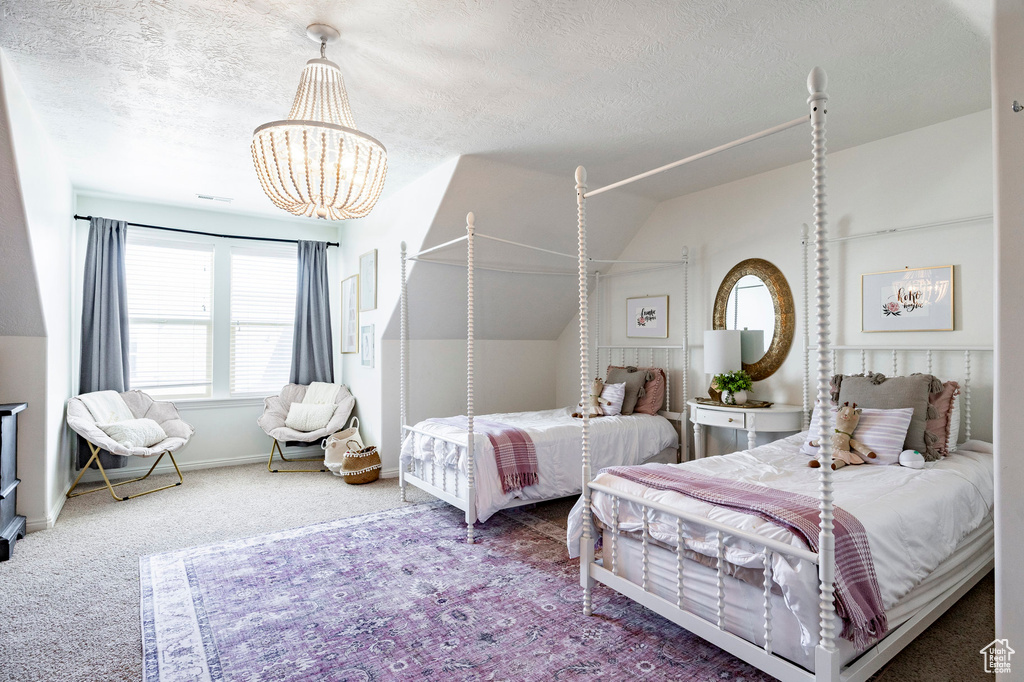Carpeted bedroom with a chandelier, vaulted ceiling, a textured ceiling, and baseboards