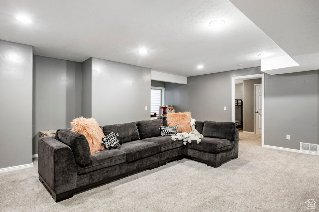 Living area featuring recessed lighting, baseboards, visible vents, and light colored carpet