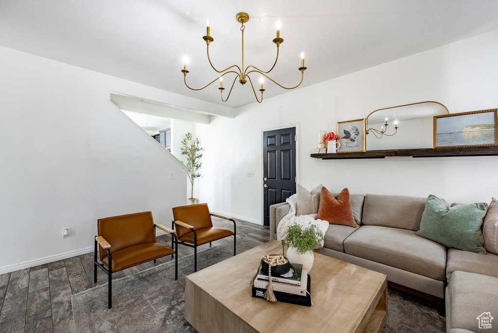 Living area featuring an inviting chandelier, dark wood-style flooring, and baseboards