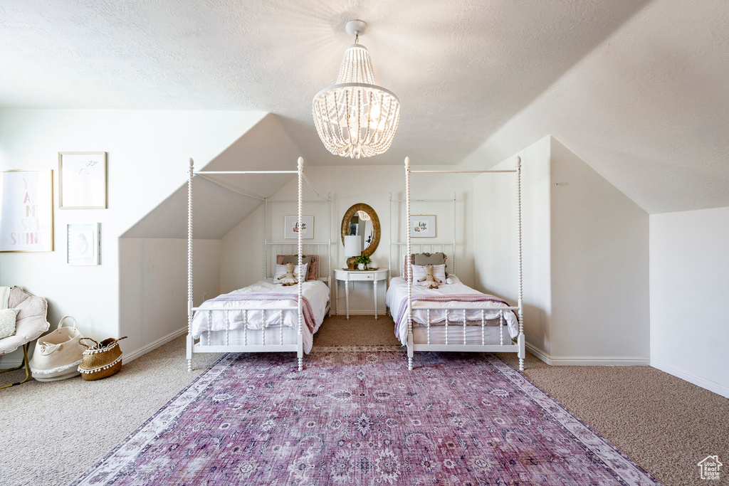 Bedroom with carpet, lofted ceiling, baseboards, and a notable chandelier
