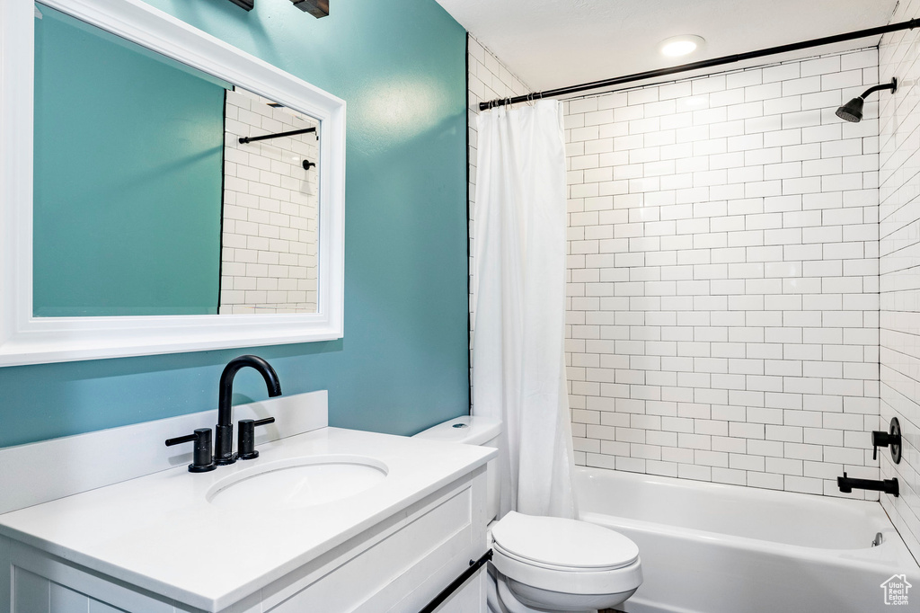 Full bath with toilet, vanity, and shower / tub combo with curtain