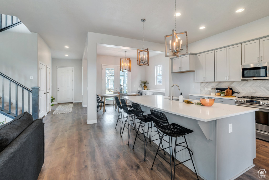 Kitchen with recessed lighting, stainless steel appliances, light countertops, a sink, and a notable chandelier