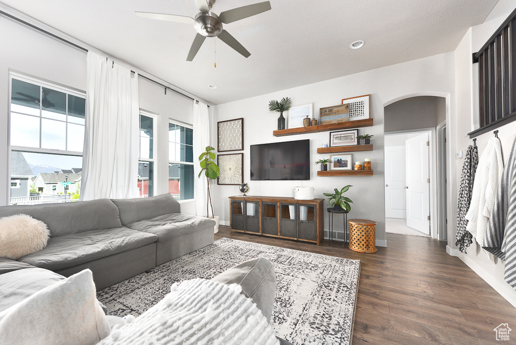 Living room with arched walkways, a ceiling fan, wood finished floors, and recessed lighting
