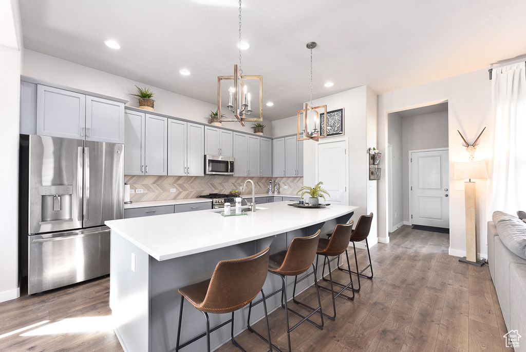 Kitchen with appliances with stainless steel finishes, a sink, backsplash, a breakfast bar area, and light countertops