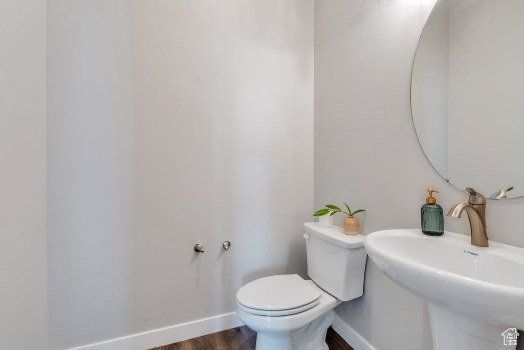 Bathroom featuring wood finished floors, baseboards, a sink, and toilet