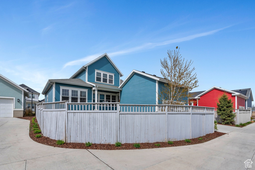 Rear view of property with a garage, driveway, and fence
