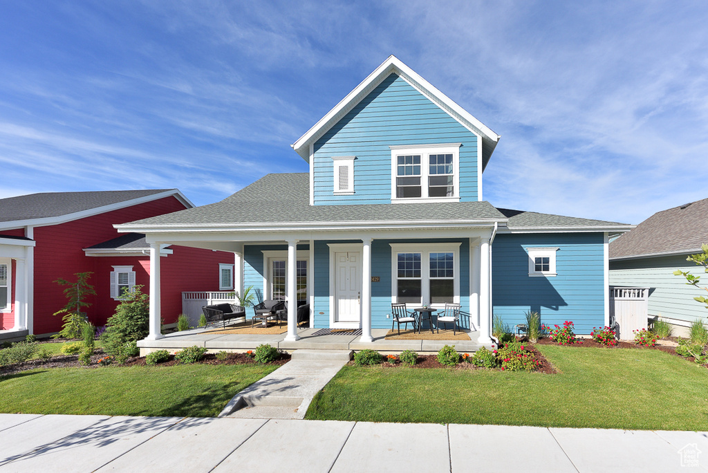 View of front of house featuring a porch, a front yard, and a shingled roof