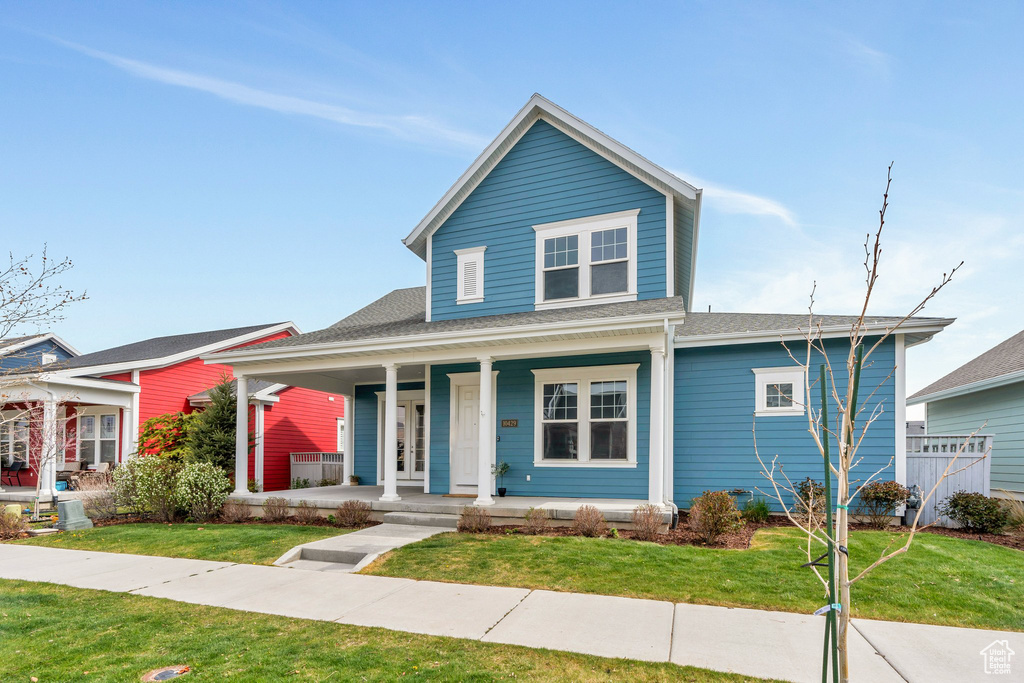 View of front of property with a porch, a shingled roof, and a front lawn