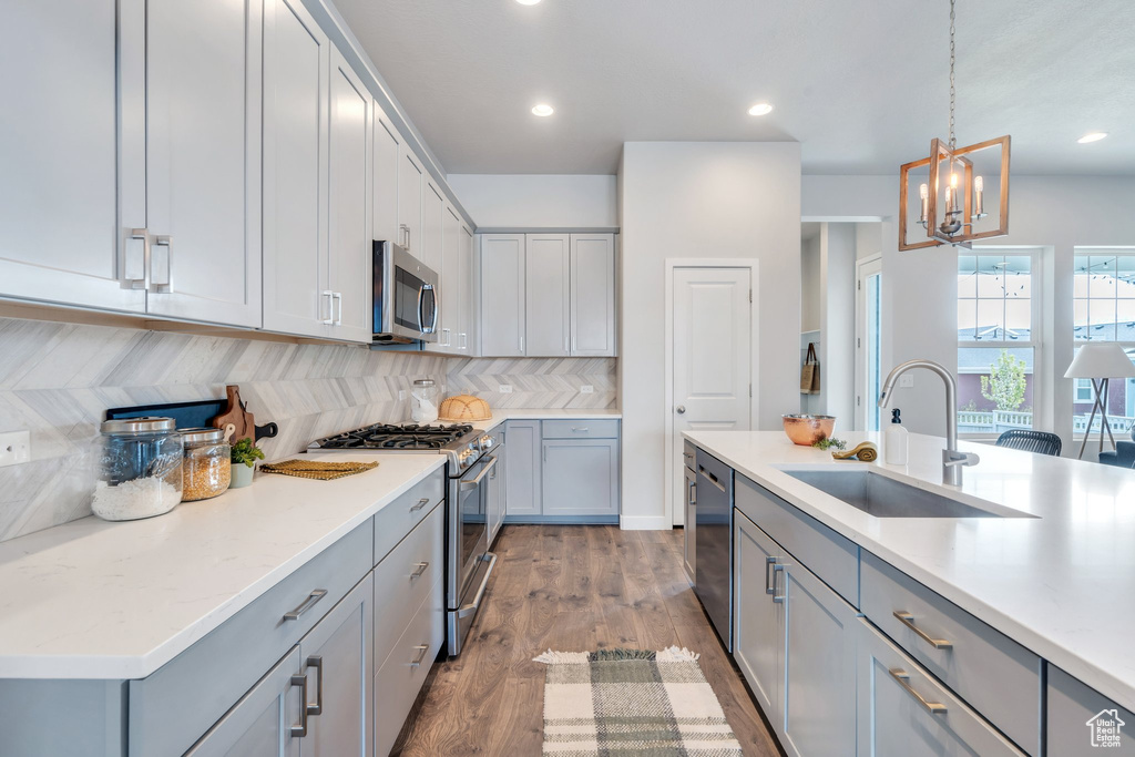 Kitchen featuring a sink, gray cabinetry, a chandelier, tasteful backsplash, and appliances with stainless steel finishes
