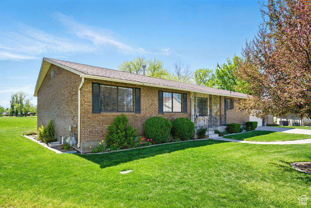 Ranch-style home featuring brick siding, a garage, and a front yard
