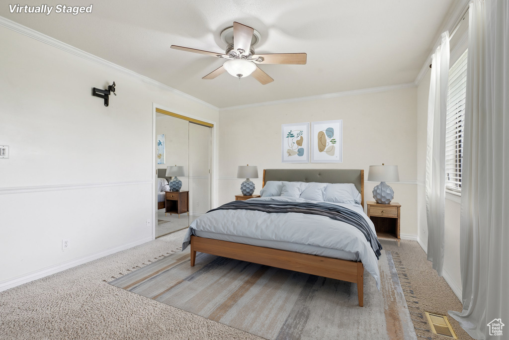 Carpeted bedroom featuring crown molding, baseboards, ceiling fan, and a closet