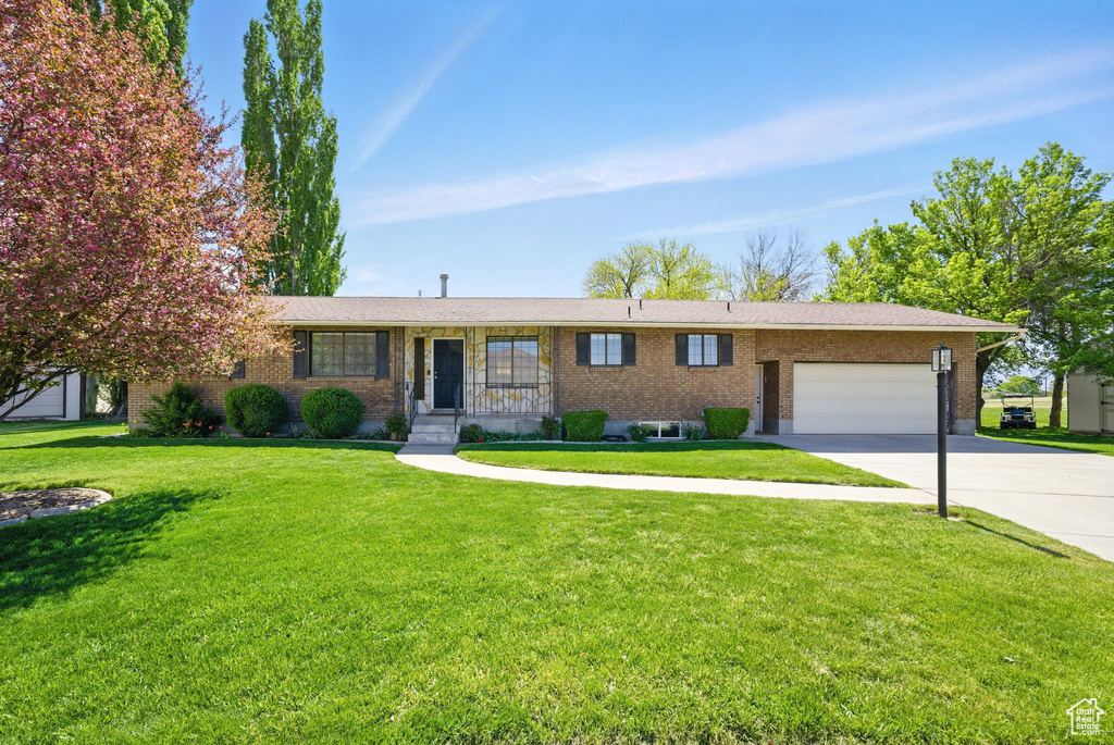 Ranch-style house with concrete driveway, brick siding, a front lawn, and a garage
