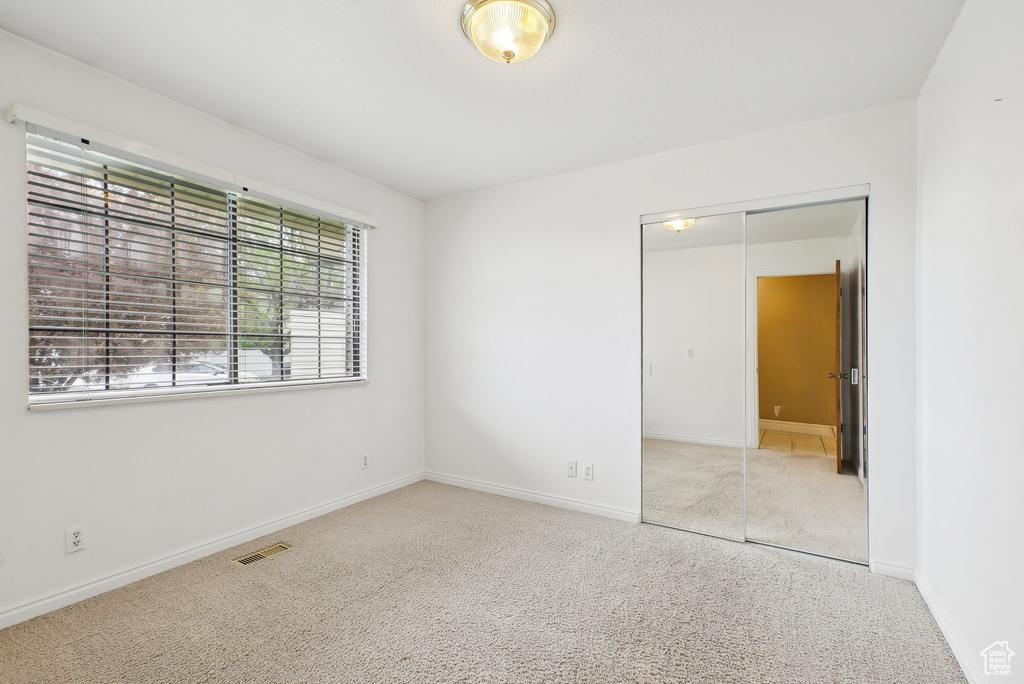 Carpeted spare room with visible vents and baseboards