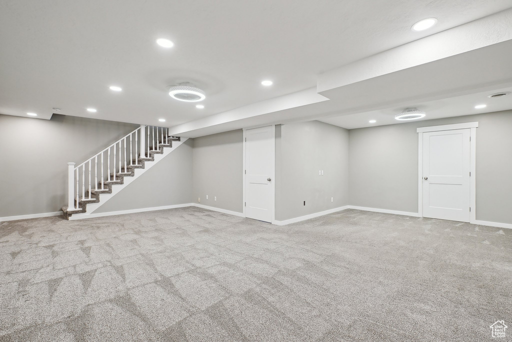 Finished below grade area with stairway, carpet floors, baseboards, and recessed lighting