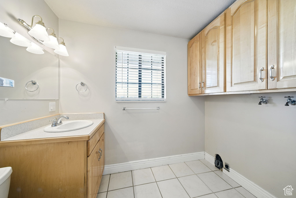 Interior space featuring toilet, tile patterned floors, baseboards, and vanity