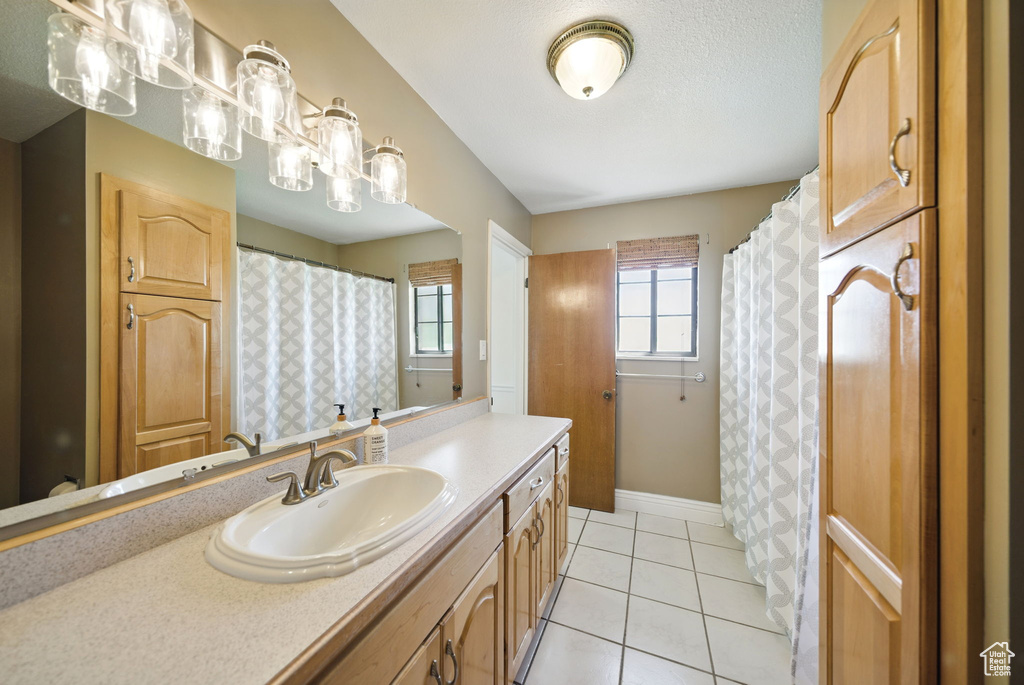 Full bath featuring vanity, tile patterned flooring, and baseboards