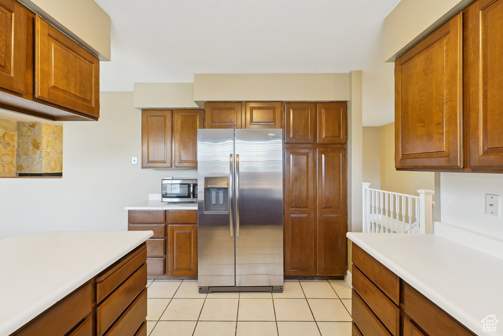 Kitchen with light countertops, brown cabinets, appliances with stainless steel finishes, and light tile patterned flooring