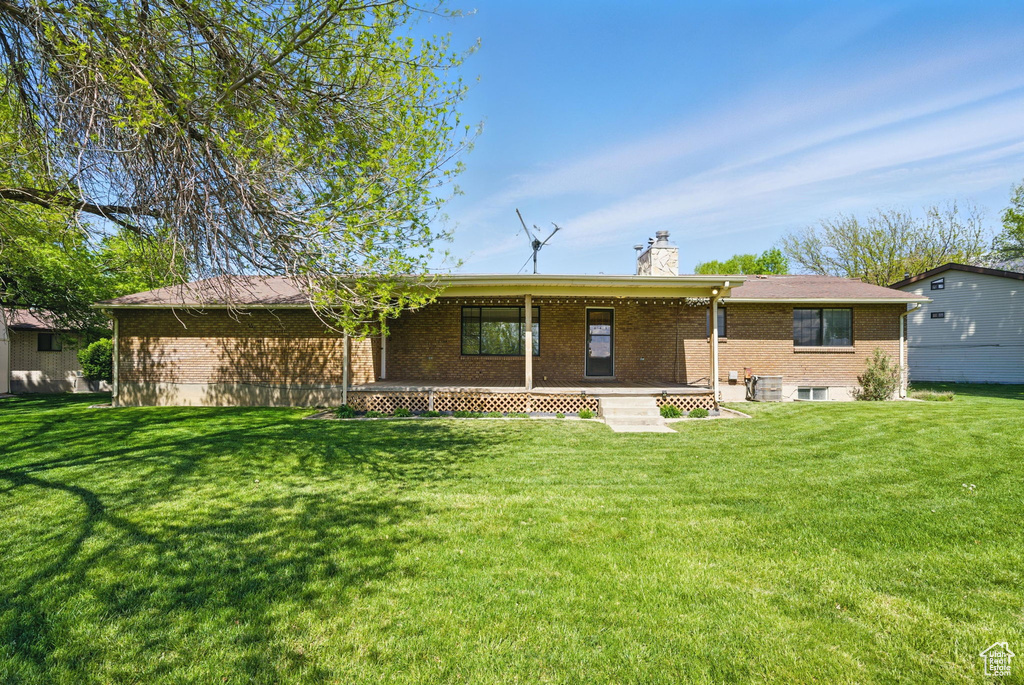 Back of house with a lawn, brick siding, and a chimney