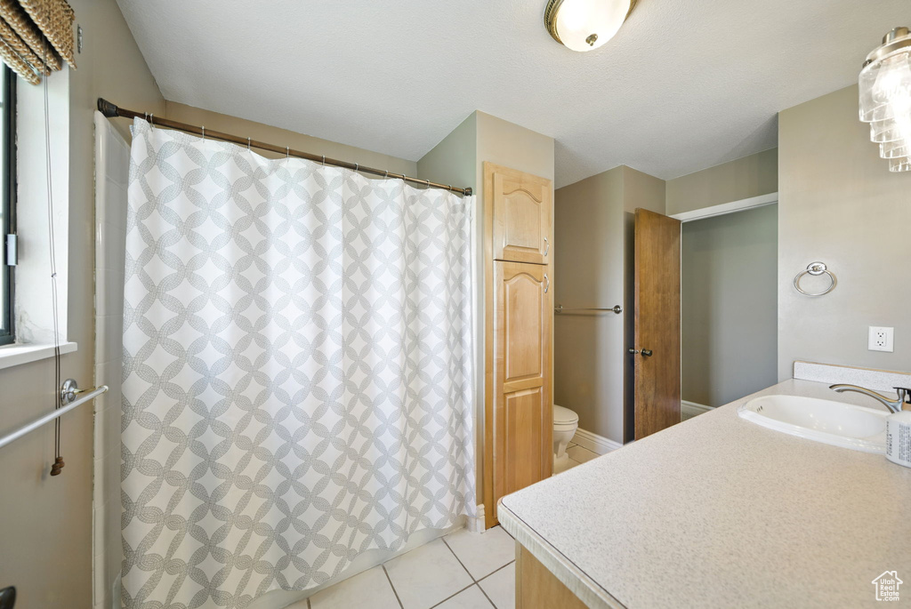 Bathroom featuring vanity, tile patterned flooring, toilet, and curtained shower
