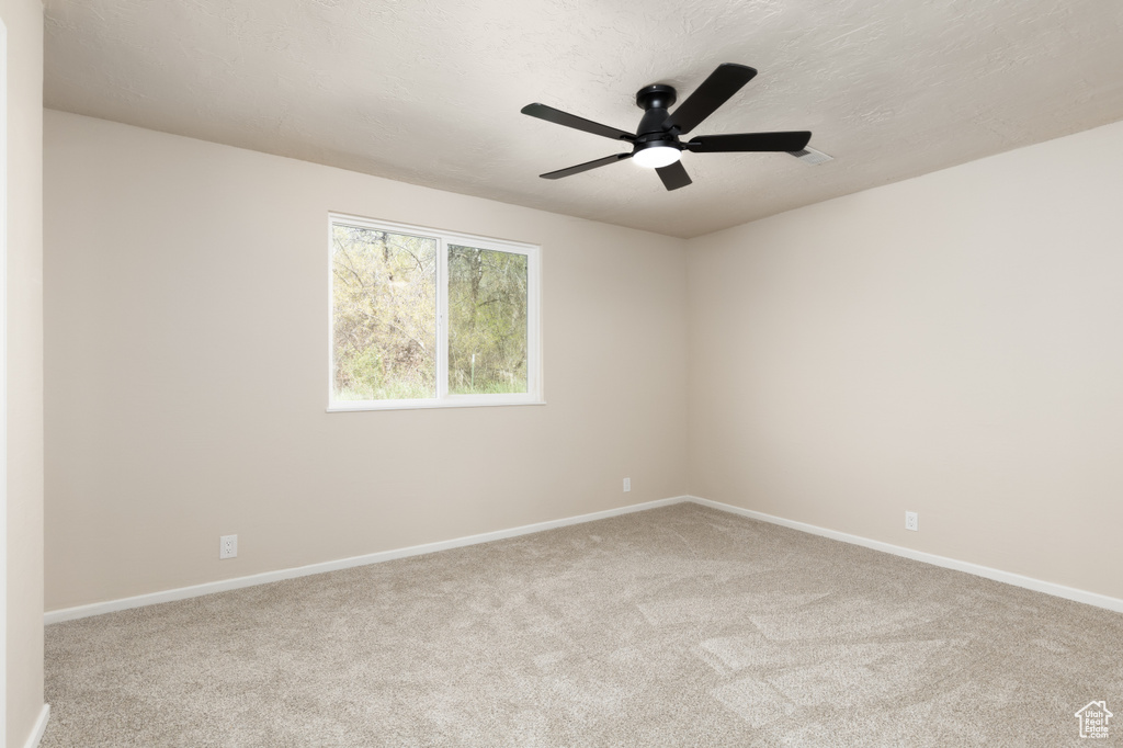 Carpeted spare room featuring a ceiling fan and baseboards