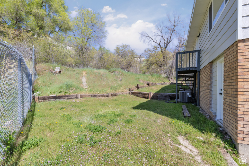View of yard with stairway, fence, and central AC
