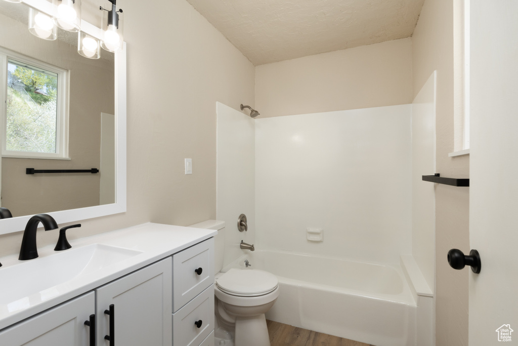 Full bath with wood finished floors, toilet, vanity, shower / bathing tub combination, and a textured ceiling