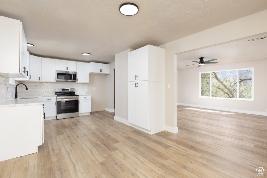 Kitchen featuring light countertops, visible vents, a sink, appliances with stainless steel finishes, and open floor plan