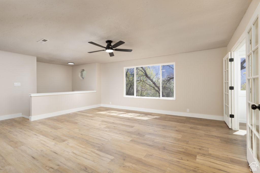 Spare room featuring light wood-style flooring, a ceiling fan, and baseboards
