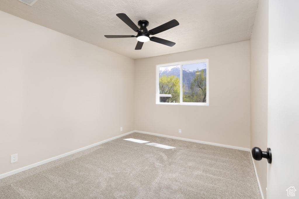 Spare room with ceiling fan, baseboards, and carpet