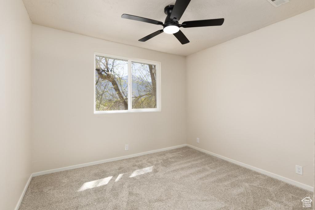 Carpeted spare room featuring baseboards and ceiling fan
