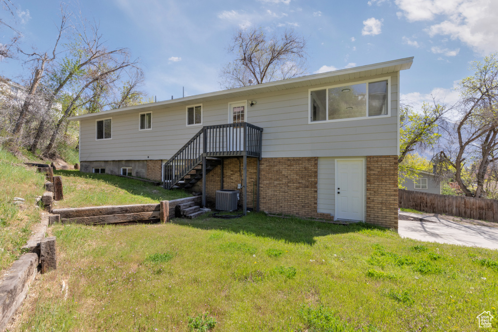 Rear view of house with stairway, fence, a yard, cooling unit, and brick siding