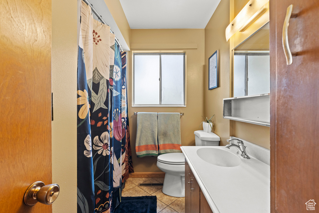 Full bath featuring vanity, a shower with shower curtain, tile patterned floors, and toilet