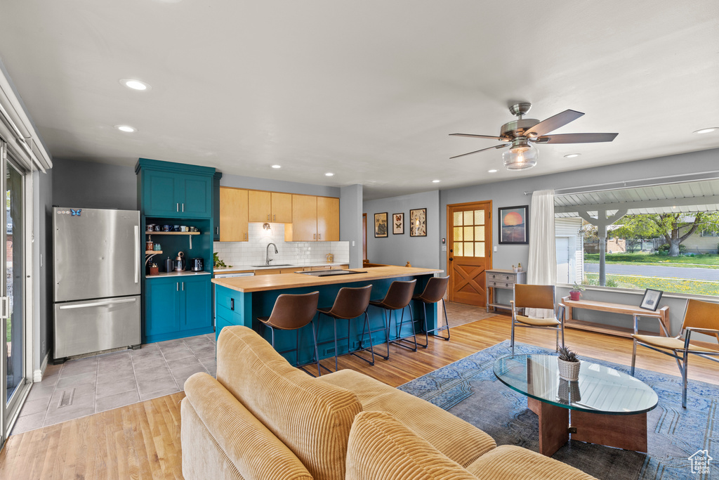 Kitchen featuring decorative backsplash, a sink, light countertops, freestanding refrigerator, and recessed lighting