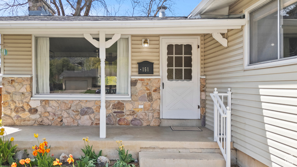 View of exterior entry featuring a chimney and stone siding