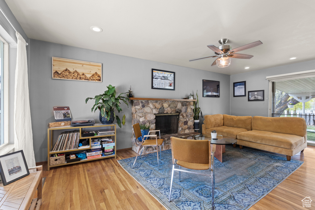Living area with a stone fireplace, recessed lighting, ceiling fan, and wood finished floors